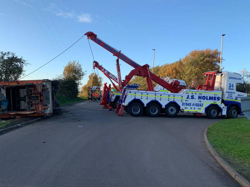 J.S. Holmes recovery trucks working together to lift a large, overturned vehicle