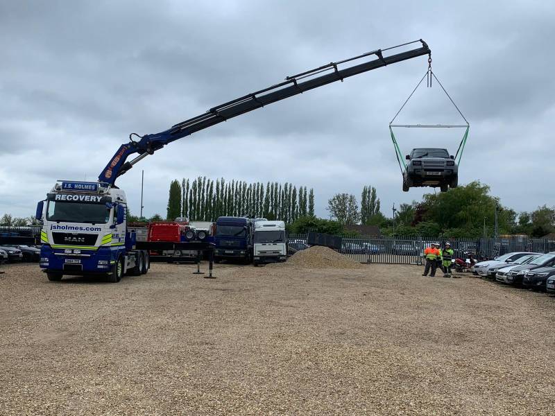 large blue recovery truck from J.S.Holmes lifting a car with its crane