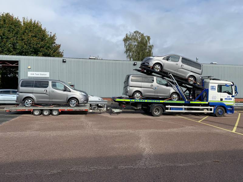 large, white recovery truck from J.S.Holmes transporting three silver vans on a trailer