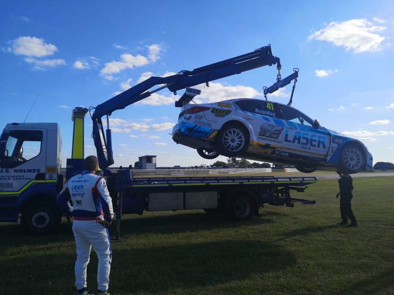 J.S. Holmes recovery truck towing a racing car on a trailer. The racing car is blue and white with the number 44 on the side