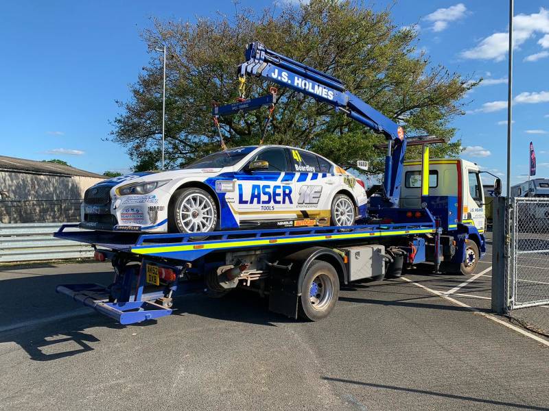 J.S. Holmes recovery truck towing a racing car on a trailer. 