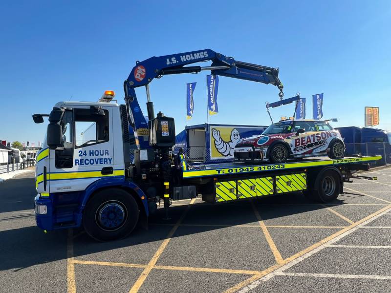 J.S. Holmes recovery truck lifting a racing car onto its trailer. The racing car is red and white with the word "BEATSON" on the side