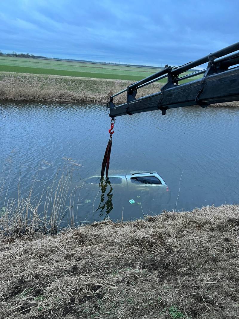 JS Holmes recovery truck using a crane to lift a car out of a canal. 