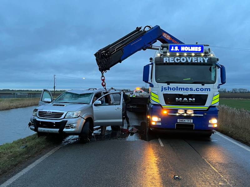 J.S. Holmes recovery truck lifting a pickup truck out of a ditch. 