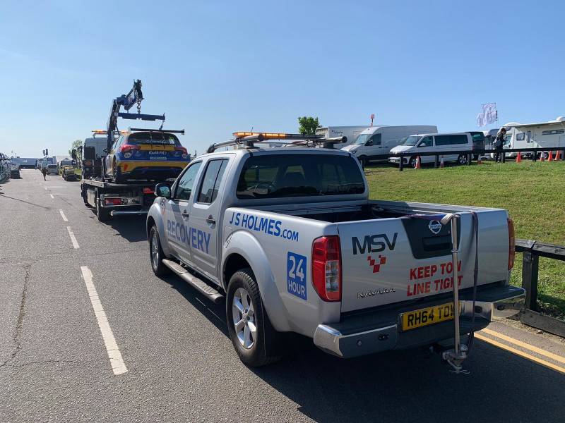  J.S. Holmes recovery truck towing a car on a trailer followed by a recovery pick up truck