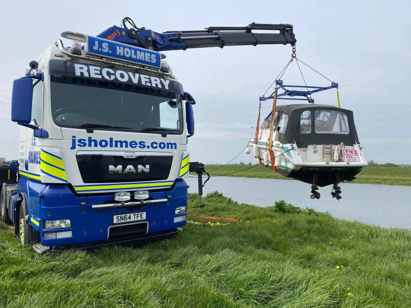 J.S. Holmes recovery truck lifting a boat out of the water. 