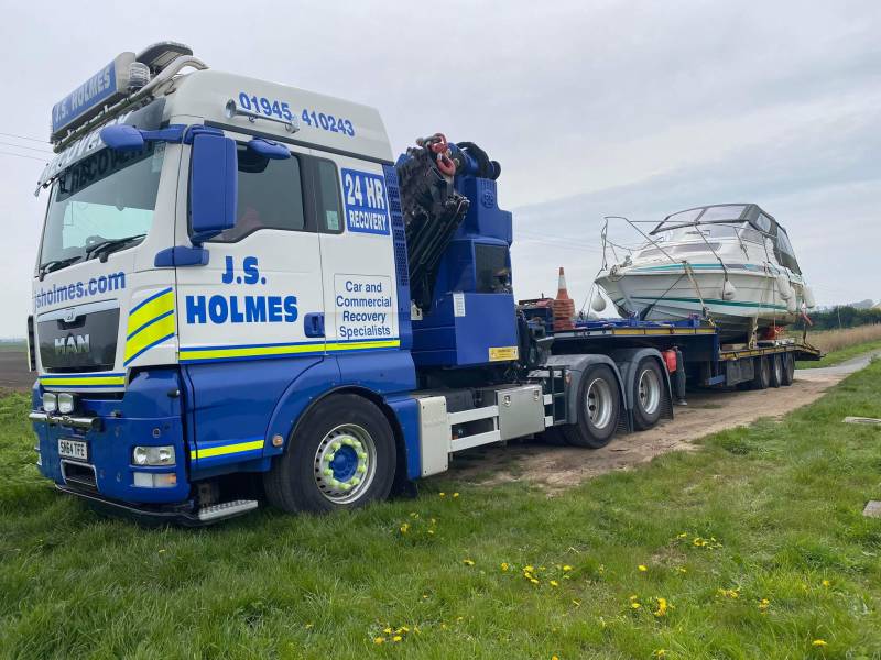 J.S. Holmes recovery truck transporting a boat on a trailer.